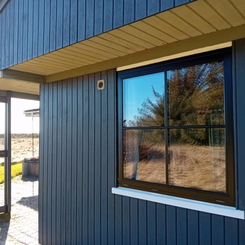 Nyudskiftet vindue med sort ramme og sprosser monteret af tømrer i sommerhus ved Nykøbing Mors.