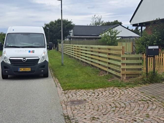Opsætning af hegn med vandrette brædder langs grund